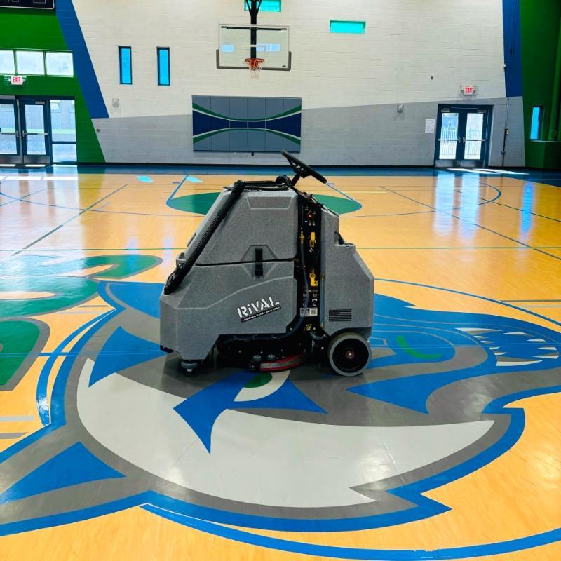 Tomcat Stand On Floor Scrubbers Rival gymnasium wood gym floor A Tomcat Rival stand on battery floor scrubber cleaning the wood gym floor of a gymnasium in Pheonix, AZ
