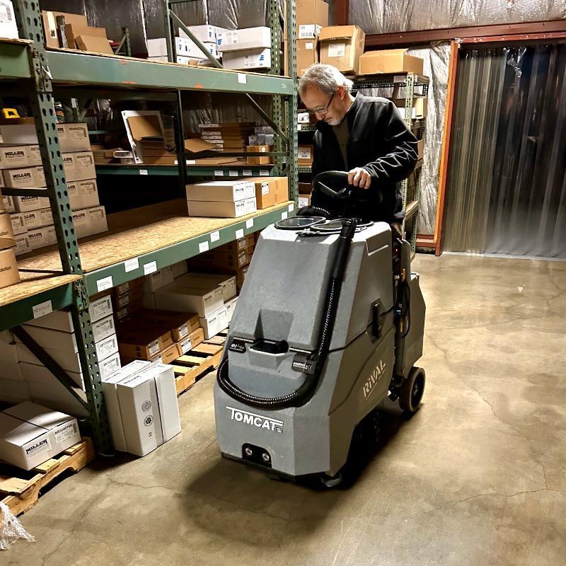 Tomcat Stand On Floor Scrubbers Rival warehouse concrete A Tomcat Rival Stand On Floor Scrubber cleans the concrete floor in the warehouse of a Normal, Illinois cleaning and janitorial supply house